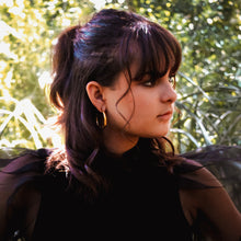 Load image into Gallery viewer, Model wearing Teuila Fatupaito Aurora Hoops, showcasing how the 18k gold plated hoops complement facial features