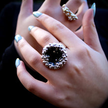 Load image into Gallery viewer, Close-up of a hand wearing Teuila Fatupaito silver ring with a dark background
