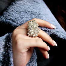 Load image into Gallery viewer, Hand wearing a large, ornate Stirling silver ring with a textured band by 'Teuila Fatupaito', against a soft gray fabric background.