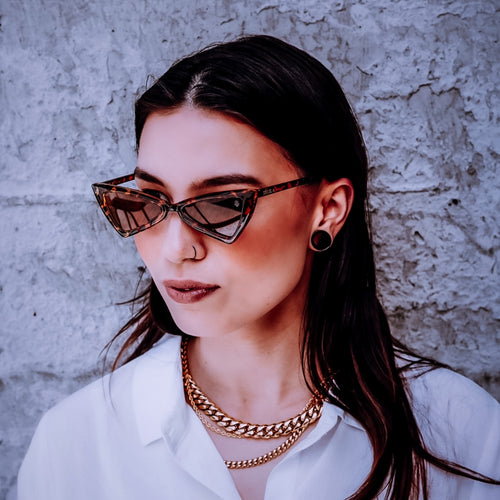Woman wearing Teuila Fatupaito Mary Jane sunglasses in shell  against a textured wall