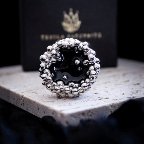 Front View Silver ring with black centre on a stone surface with a dark background by Teuila Fatupaito Jewellery 