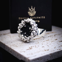 Load image into Gallery viewer, Side view Silver ring with black centre on a stone surface with a dark background by Teuila Fatupaito Jewellery 
